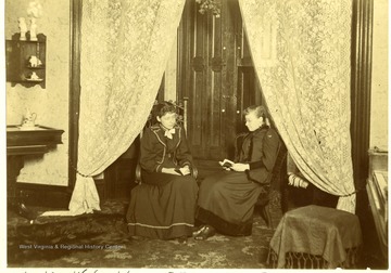 Laura and Jessie Burt read in the sitting room in their home on Island and South Broadway Streets in Wheeling, W. Va.