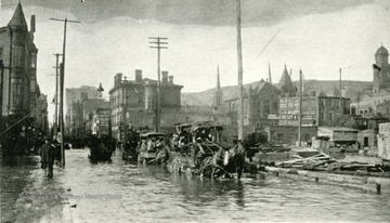 Market Street, looking North from 17th Street in Wheeling. Horses and carriage can be seen wading through flood waters. 