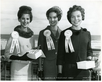 Miss West Virginia is holding a glass bell.  Miss California and Miss Missouri are also present.