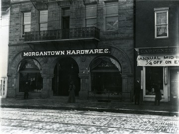 The Morgantown Hardware Company building on High Street. People in front of buildings walking on the sidewalk. 