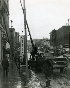 Men seen working on a building on High Street in Morgantown, W. Va. Hanging a sign. 