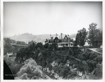 The exterior view of Senator J.H. McDermott's house on Kirk Street in Morgantown, West Virginia. Below the house are railroad tracks and a smaller house.