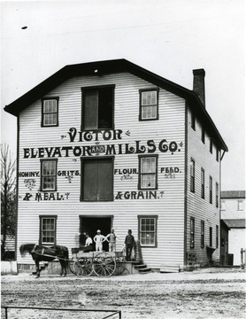 Victor Elevator and Mills Company located in Morgantown, W. Va. Horse and wagon seen in front of mill along with a small group of men.  