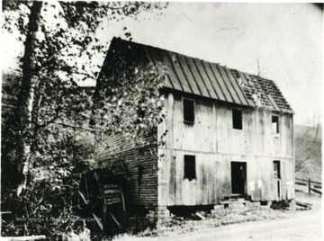 An exterior view of a mill. An old water mill seen to the left of the structure. 