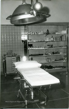 Emergency Room? A clean bed is seen surrounded by supplies and a light.