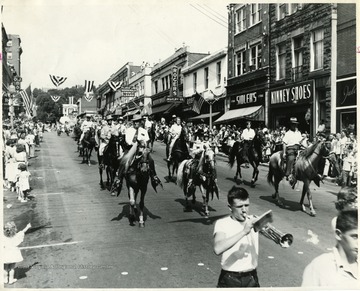 People on horses ride down High Street for a parade.