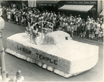 Three women in dresses ride the Labor Temple float.