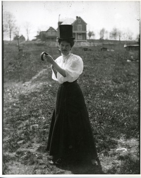 Woman is standing in a field in Morgantown, West Virginia. Two houses are pictured in the background.
