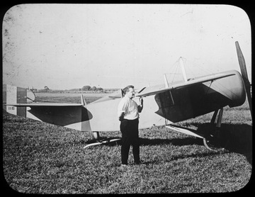 World War I Lantern Slide Show. Slide No. 19 in group of originally numbered slides.  Man standing in front of single wing aircraft.  Frame is labelled with text saying 'Visual Bureau, University of Pittsburgh.'  (negative no. 19-1315 is inscribed on slide)<br />