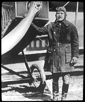 World War I Lantern Slide Show. Slide No. 24 in group of originally numbered slides.  Portrait of pilot standing in front of biplane with hand on the propeller.  Frame is labelled with text saying 'Visual Bureau, University of Pittsburgh.'  (negative no. 24-5963 is inscribed on slide)<br />
