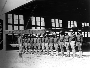 World War I Lantern Slide Show. In group of originally numbered slides.  (Number label is lost.)  American student pilots standing at attention in front of a biplane in a hanger.  (negative no. L-10975 is inscribed on slide)<br />