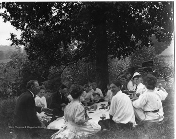 People are enjoying a picnic. 'Harry Selby out of focus in foreground.'