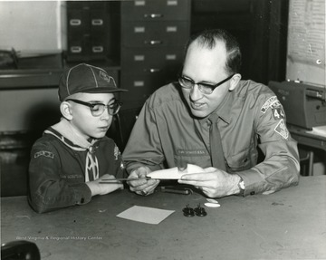 A Cub Scout and his Den Leader are working together to build a model car. 