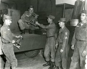 Men in the National Guard unloading equipment from a truck.