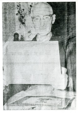 'Hard to see on original print, but it looks like he's holding a newspaper. The gentleman worked on the Laurel Fork and Sand Hill Railroad. This picture comes from a Parkersburg Sentinel article chronicling his experience. Parkersburg News July 10, 1960, page 6.'--Mike Naylor, 03/2006.