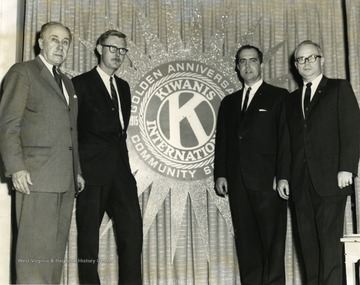 Members of the Kiwanis Club stand near the Golden Anniversary Seal. Members include from left to right: 'Arthur Buehler, Edward V. McMichael, Foster Mullenax, and Don Bond.' 