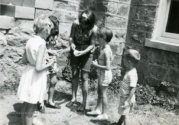 'Barbara Beavers, one of approximately thirty playground supervisors employed by the recreation commission during the summer program, demenstrates foam-craft techniques to youngsters at Evansdale Playground.'