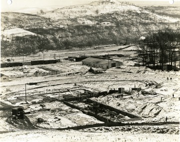 'Morgantown Ordnance Works, Morgantown, W. Va. Photograph Number 112. March 17. 1941, 3:00 P.M. Taken from tower number 1. Looking Southeast in maintenance shops and stores and construction pipe shop in background. Service building and main office in foreground.'