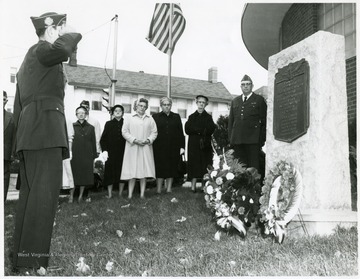 Group of people stand next to a monument with a plaque on it.