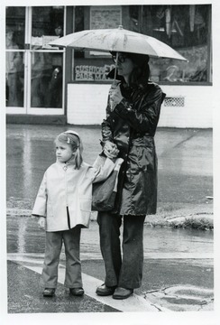 Woman with an umbrella holds the hand of a small girl.