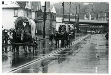 Covered wagons being pulled by horses down Beechurst Avenue.