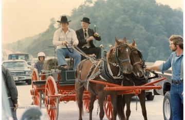 Two horses are pulling a wagon with two men during the Monongalia County Bicentennial Parade in Morgantown, West Virginia.