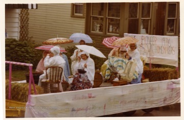 A group of women from the Pioneers Women Homemakers Club with umbrellas on their float.