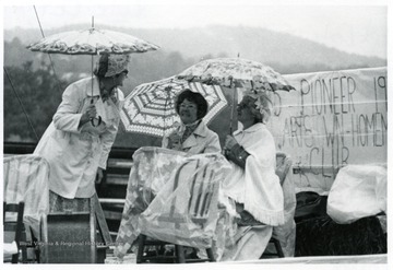 A group of ladies in period clothing holding umbrellas.