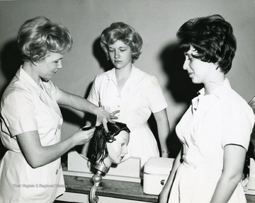 Female students practicing on fake hair. Woman on the left is 'E. Joy Lynch'. 
