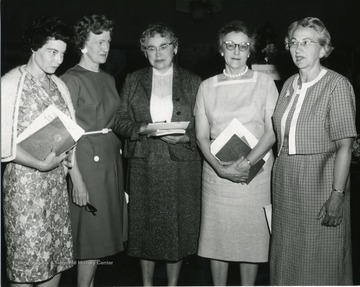 Women standing together holding books and paper. Second from right is Hilda Dailey. 
