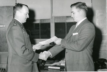 'William Carr, son of Mr. and Mrs. Ralph A. Carr of Mannington and the husband of the former Miss Sheila Dian Bierer of Morgantown, is congratulated by Colonel A. H. Davidson, Jr., Director of the U. S. Army Engineer Research and Development Laboratories, Fort Belvoir, Virginia, upon receiving an 'Outstanding' work performance rating.' 'Technical Liaison Office, U.S. Army Engineer Research and Development Laboratories.'