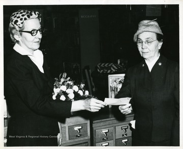 Two women hold a check.  One of the women is Nellie Rider, member of the Friends of the Morgantown Public Library.