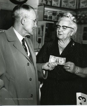 Mr. Tucker is giving Mrs. Bonfili a dollar.  (Mrs. Bonfili owned a grocery store.  Her son played football at Morgantown High School and West Virginia University, and coached the MHS football team.  This information came from Mr. Chico, a Morgantown photographer, on 5-4-2006.)