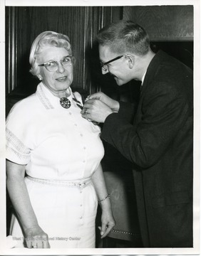 Martin Dadisman, the outgoing Chairman is pinning Mrs. O.J. White, the new Chairman Rehabiliation Committee 1961/62.