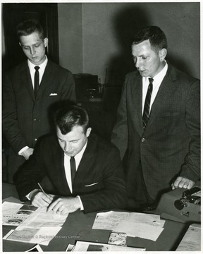 Unidentified man appears to be signing a document or filling out a form.  No details are available.