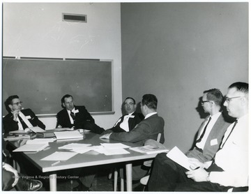 Men seated around a table in discussion.