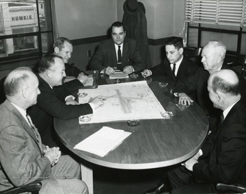 Members of the City Council sit around a table discussing a map.