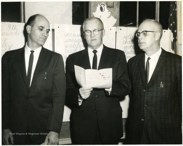 Man in center holding the 'Save Our Schools' pamphlet is Dr. Harold Kerr. All three may be part of the School Board.