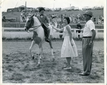 A young boy wins an equestrian ribbon.