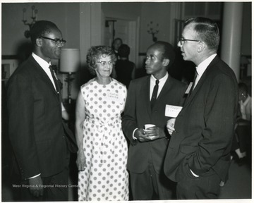 Four people having a conversation at an event. Lydia Lemke stands in between two African-American men.