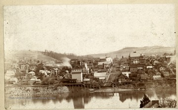 'Morgantown from across the Monongahela River sometime in the late eighties. Note unpaved Walnut Street and the River Wharf. To the left of which can be seen the bell tower on Old Monongalia Academy then used for the public school, and the old Fire Shed jutting out into the street. Property of Jas. R. Moreland.'