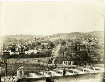 A view of Morgantown, West Virginia from the south. A man is walking near a wooden fence.