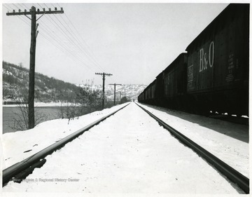 Tracks running along the Monongahela River and railroad cars on the right of the tracks.