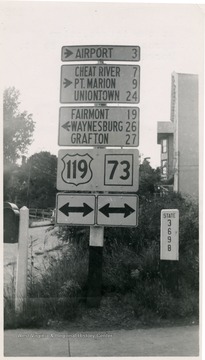 Highway signs to the airport, Cheat River, Point Marion, Uniontown, Fairmont, Waynesburg, and Grafton at the Intersection of Spruce St. and Willey St., Morgantown, W. Va.