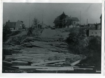 A stack of lumber can be seen behind several houses at an unknown location in Morgantown, West Virginia.