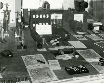 A table top covered with investigation equipment. In the center, there is a 'fingerprint and criminal investigation kit'.