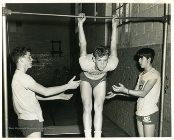 Two boys are spotting a boy on the uneven bars during their gym class in Riverside Junior High in Morgantown, West Virginia.