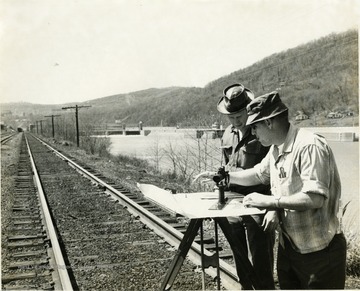Men standing with surveying equipment next to the Baltimore and Ohio Railroad tracks and the Monongahela River.