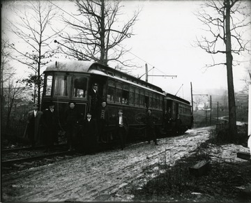 Several passengers are standing besides a Sabraton Railway car in Morgantown, West Virginia.