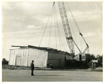 Cranes lift sections of a hangar at the Morgantown Airport.